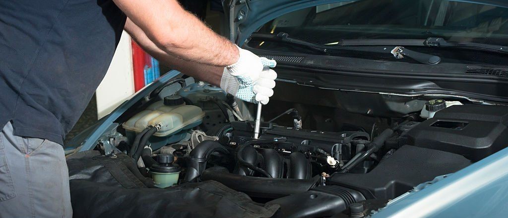 mechanic repairing kia car engine with white gloves