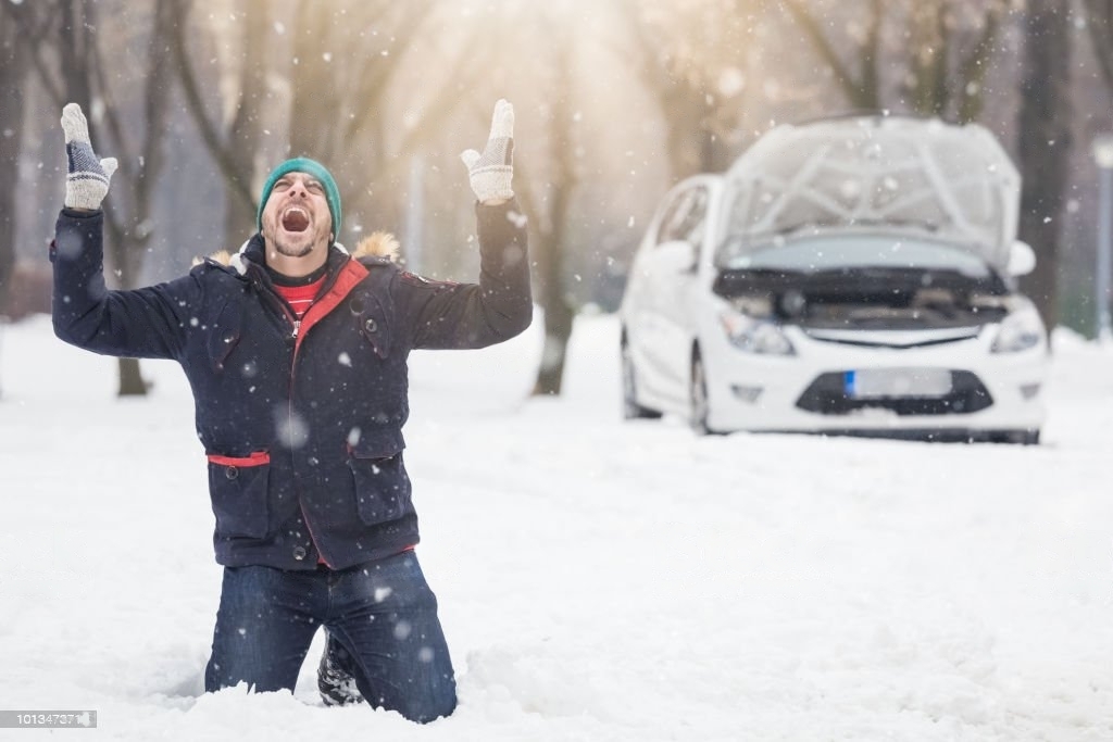 Frustrated driver next to broken car in winter season